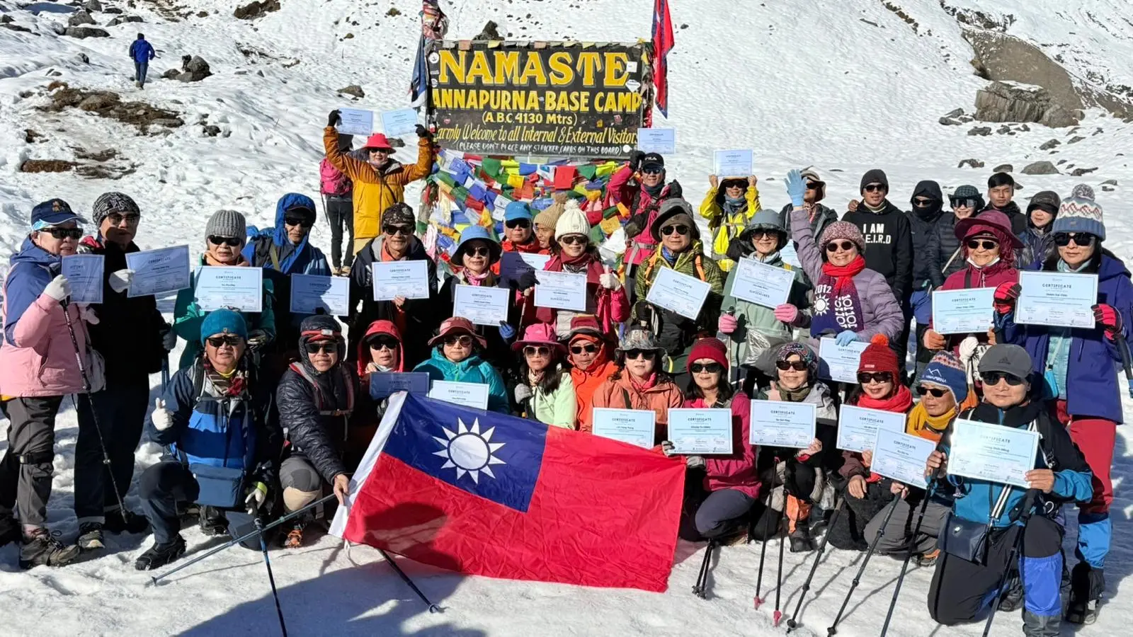Group of Taiwanese trekkers celebrating their arrival at Annapurna Base Camp. The photo captures the iconic ABC trek destination in Nepal with majestic Himalayan mountains in the background