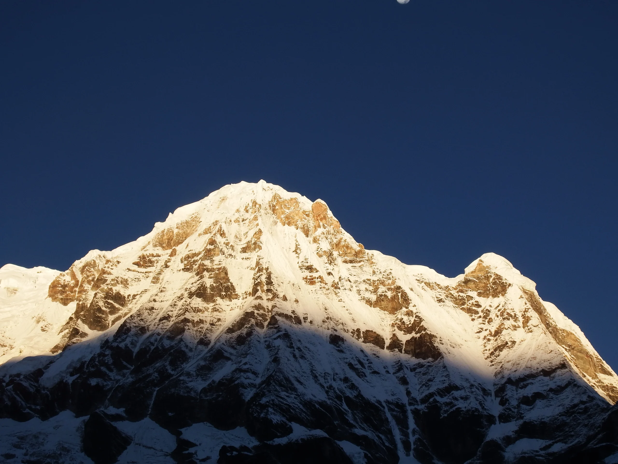 Close-up view of Annapurna South summit with sunrays hitting the snow. A primary mountain landmark captured during the Annapurna Base Camp trek in Nepal.