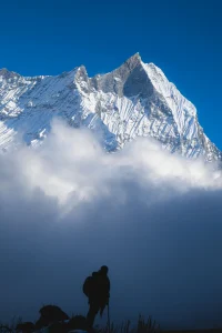 A silhouette of a trekker standing on a ridge, gazing at a majestic snow-covered Himalayan peak rising above the clouds under a clear blue sky. A silhouette of a trekker standing on a ridge, gazing at a majestic snow-covered Himalayan peak rising above the clouds under a clear blue sky. A silhouette of a trekker standing on a ridge, gazing at a majestic snow-covered Himalayan peak rising above the clouds under a clear blue sky. 