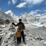 A solo trekker gazing at snow-covered Himalayan peaks during twilight, surrounded by remote valleys—capturing the serene experience of treks in Nepal.