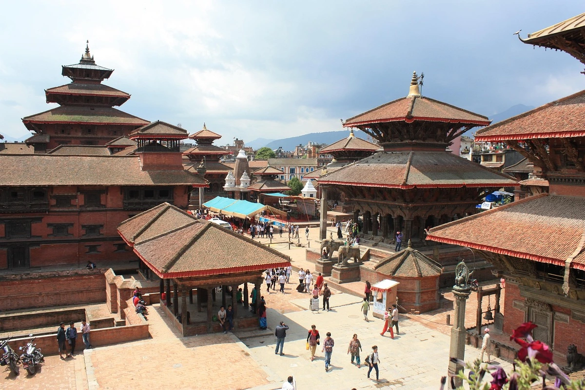 A vibrant scene at Kathmandu Durbar Square featuring ancient red-brick temples with multi-tiered pagoda roofs, showcasing the intricate architecture and cultural richness of Kathmandu Valley temples.