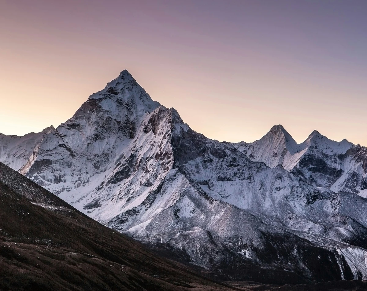 Snow-covered Himalayan peaks glow under a soft sunrise sky in Sagarmatha, one of the most iconic Nepal national parks and home to Mount Everest and breathtaking alpine scenery.