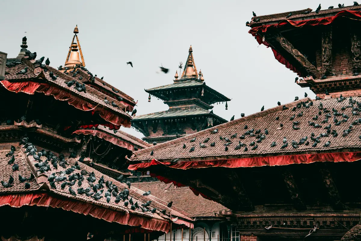 A captivating view of the ancient temples at Kathmandu Durbar Square, with traditional tiered rooftops adorned with pigeons and intricate woodwork showcasing Nepal’s timeless heritage, best explored during the best time to visit Nepal.