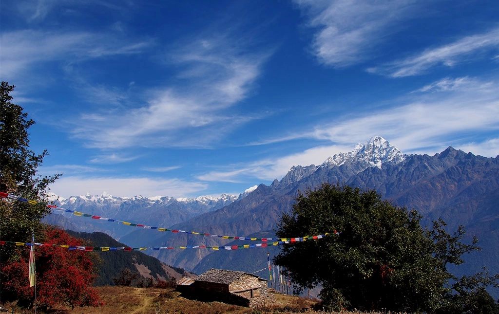Langtang Lirung mountain range with a building and trees showing culture and nature of the Langtang region.