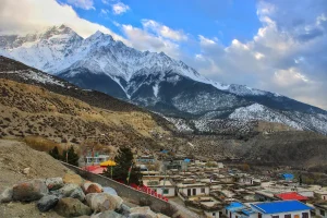 Traditional Himalayan village beneath snow-capped peaks on the Dhaulagiri Circuit Trek, showcasing the remote mountain landscapes and local culture of western Nepal.